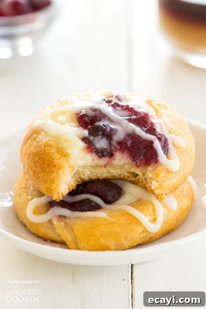 Cranberry Cream Cheese Pastries: Crescent roll dough is filled with vanilla cream cheese, tart cranberry sauce and a drizzle of sweet icing. Cranberry Cream Cheese Pastries with a bite taken out