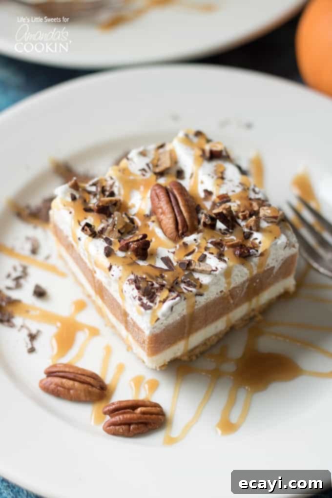 This Pumpkin Lasagna has a graham cracker crust, a sweet cream cheese layer, pumpkin spice Jello pudding, Cool Whip and topped with pecans. slice of pumpkin dessert on plate