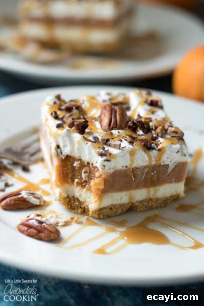 This Pumpkin Lasagna has a graham cracker crust, a sweet cream cheese layer, pumpkin spice Jello pudding, Cool Whip and topped with pecans. slice of pumpkin dessert with a bite out of it on plate