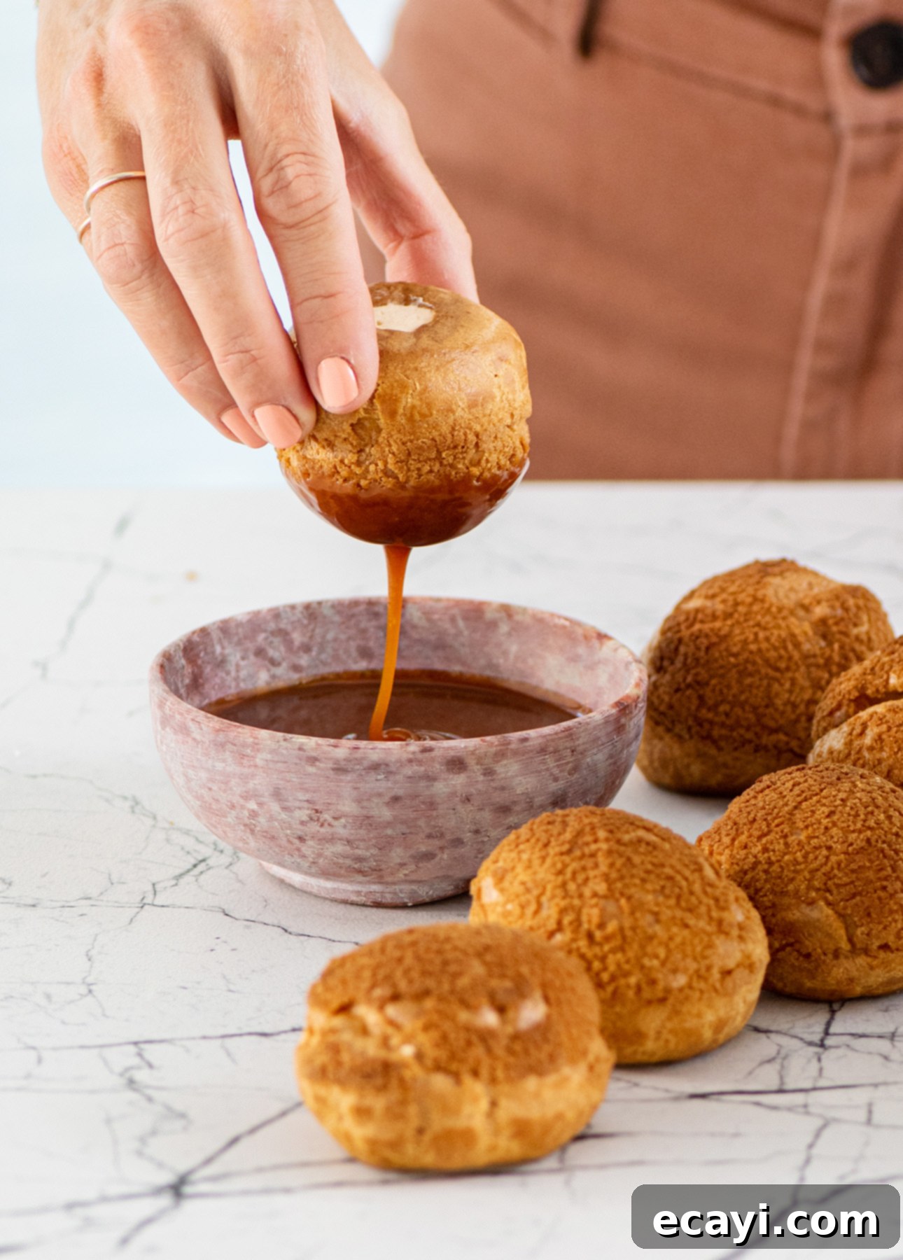 Close-up of a stack of fresh salted caramel cream puffs, highlighting the craveable caramel topping.