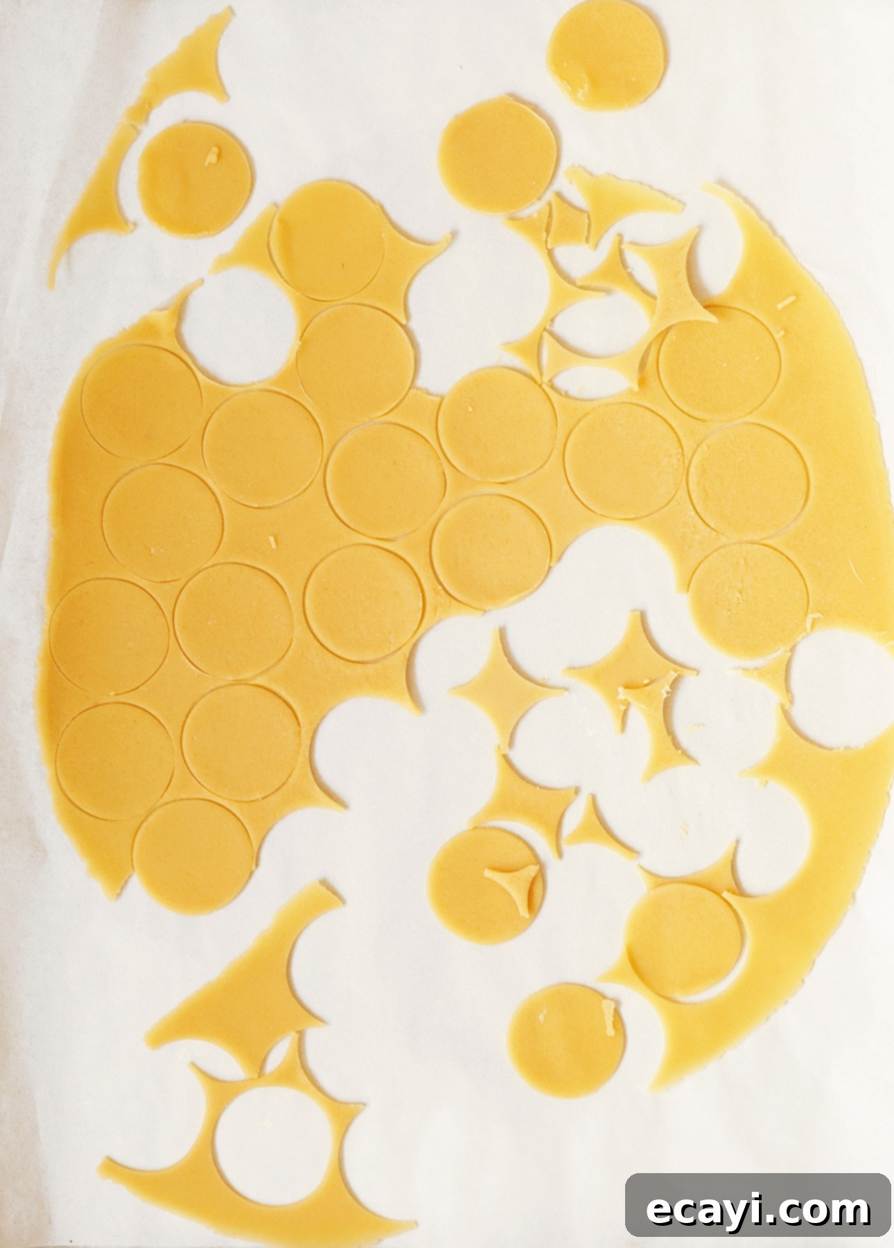 Close-up of craquelin dough circles on parchment paper, ready to be placed on choux pastry.