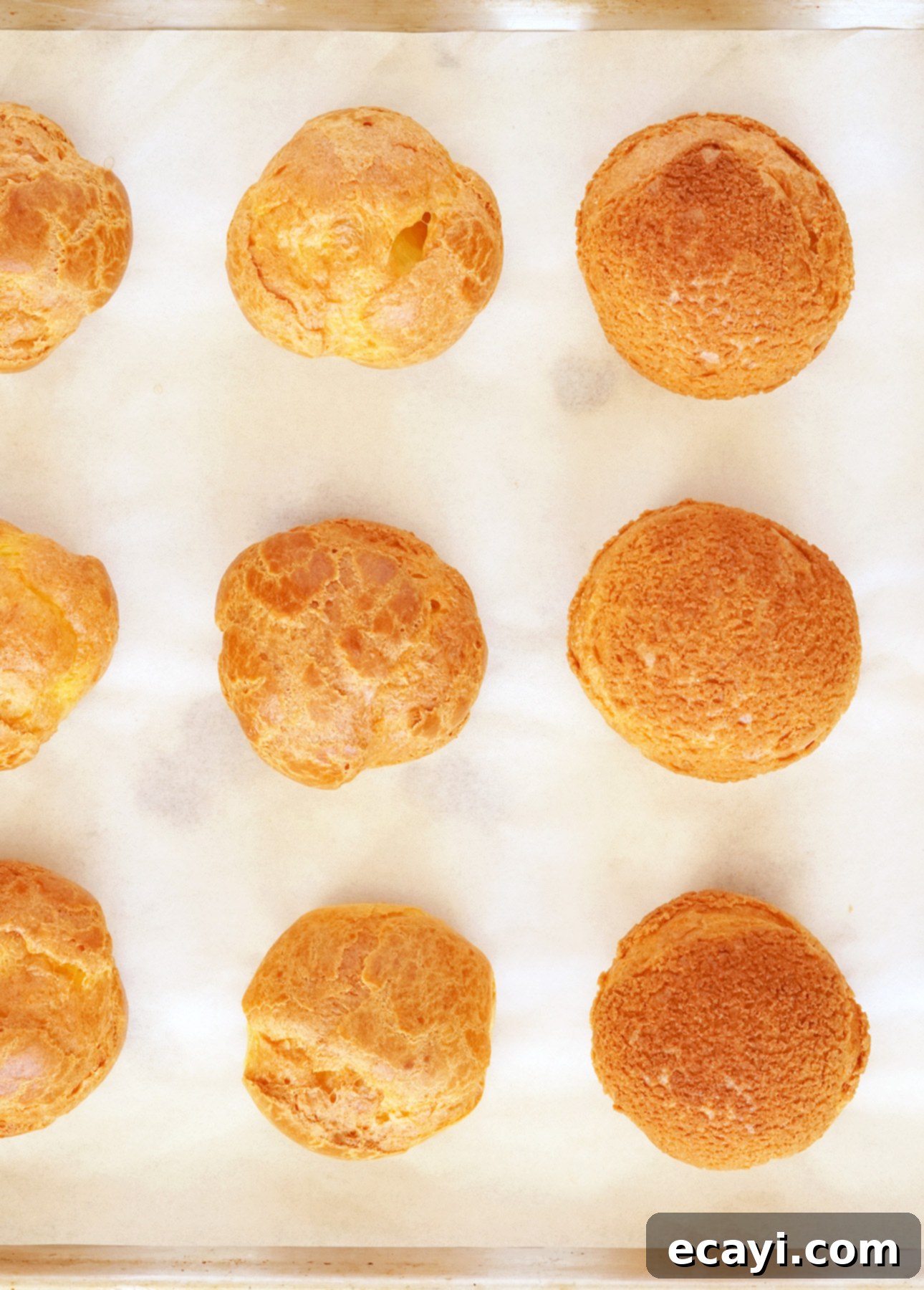 Comparison of cream puffs: one side with craquelin (right) showing a perfectly round, crisp top, and the other side without craquelin (left) showing a more rustic shape.