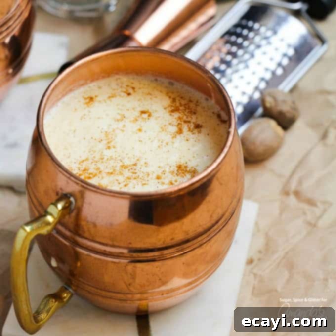 Homemade Eggnog Cocktail: A thick, rich, and flavorful holiday drink made with eggs, sugar, milk, cream, rum, and nutmeg. Perfect for your festive party. A beautifully presented homemade eggnog cocktail in a polished copper mug, garnished with a sprinkle of fresh nutmeg, ready to be enjoyed.