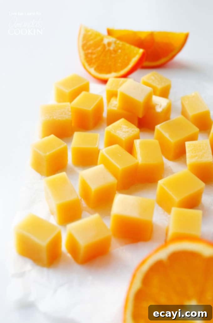 Homemade Orange Creamsicle Gummies with fresh orange slices Vibrant orange creamsicle gummies arranged with fresh orange slices, showcasing their appealing homemade texture.