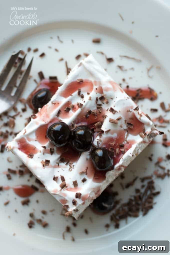 This Red Velvet Lasagna is a layered, no-bake dessert recipe with a crunchy graham cracker crust, cream cheese layer and a red chocolate pudding layer. #lasagnadessert #dessert #dessertrecipes #redvelvet #onepandessert #valentinesday #chocolate #nobakedessert Top-down view of the vibrant red velvet lasagna dessert in a baking pan, showing the smooth whipped topping and decorative chocolate shavings