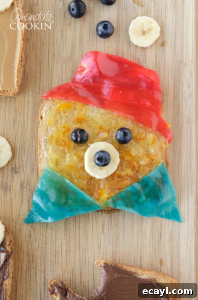 Whip up this charming bear toast in under 10 minutes—it's the perfect quick and fun food-craft to enjoy with your children! Close-up of three slices of Paddington Bear toast, each decorated with fruit and spread to resemble the charming bear, on a white plate, ready for a happy breakfast.