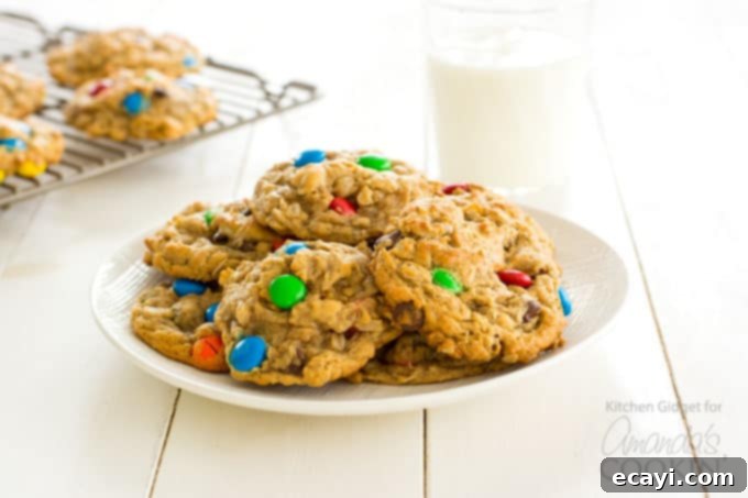 Monster Cookies: peanut butter and oatmeal cookies packed with chocolate chips and colorful M&M's. These cookies are fun to make with the kids! #monstercookies #m&ms #cookierecipes #bestdessertrecipes #chocolate #peanutbutter #peanutbuttercookies #oatmeal #oatmealcookies Monster Cookies served on a plate with a glass of milk