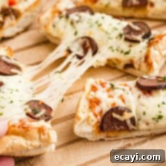 Ultimate French Bread Pizza 3 Close-up of a French bread pizza with melted cheese pulling away from the slice