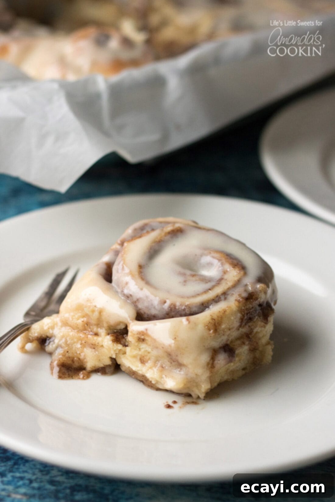These Homemade Cinnamon Rolls are a true classic. Topped with cream cheese frosting, these gooey cinnamon rolls satisfy your sweet craving! They also make the perfect holiday morning breakfast with the family. #breakfast #cinnamonrolls #breadrecipes #holidaybreakfast #dough #cinnamon Homemade Cinnamon Roll on a plate, ready to be enjoyed