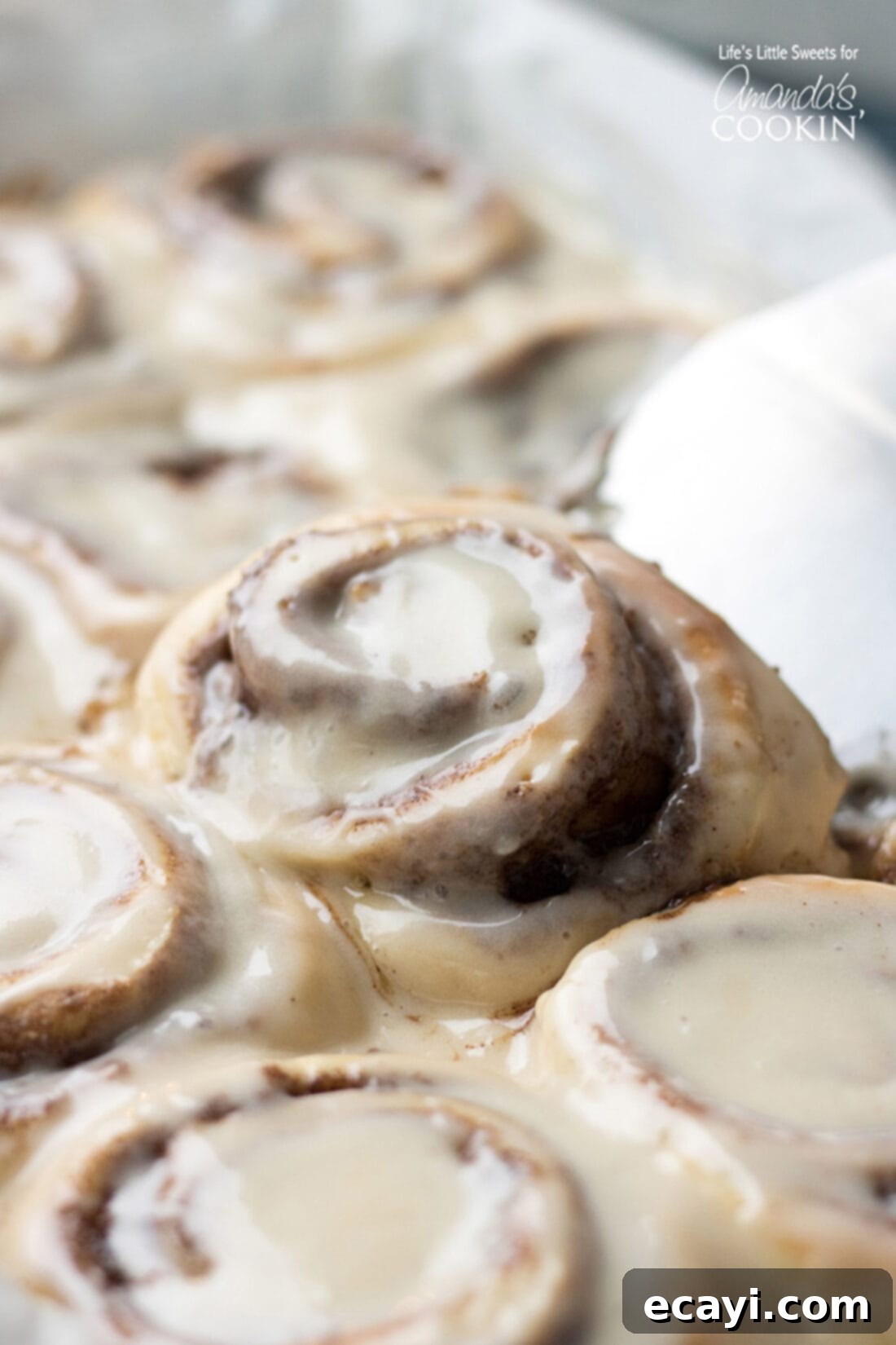 These Homemade Cinnamon Rolls are a true classic. Topped with cream cheese frosting, these gooey cinnamon rolls satisfy your sweet craving! They also make the perfect holiday morning breakfast with the family. #breakfast #cinnamonrolls #breadrecipes #holidaybreakfast #dough #cinnamon Homemade Cinnamon Roll being lifted out of the pan, showing its gooey texture
