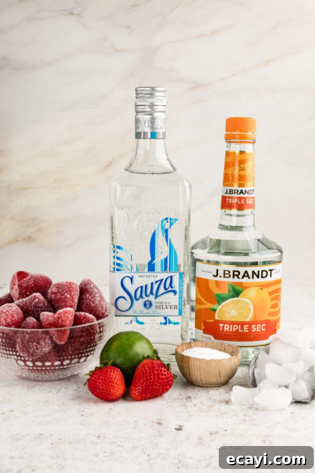 Berry Burst Margarita 4 A curated display of ingredients for strawberry margaritas, including frozen strawberries, tequila, triple sec, limes, and a shaker.