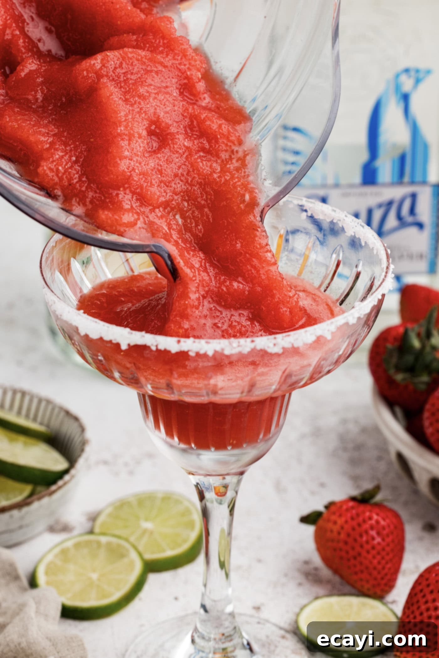 Berry Burst Margarita 10 Pouring the vibrant frozen strawberry margarita slush from the blender directly into a prepared, salt-rimmed glass.