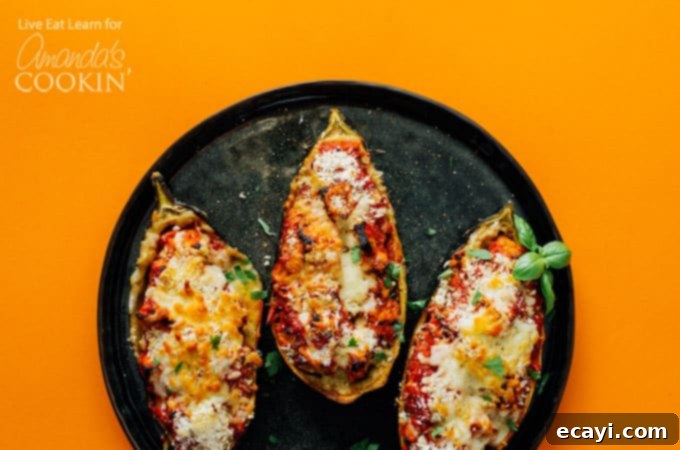 Cheesy Stuffed Eggplant Parmesan 4 Three stuffed eggplant halves on a black plate, with steam rising from them.