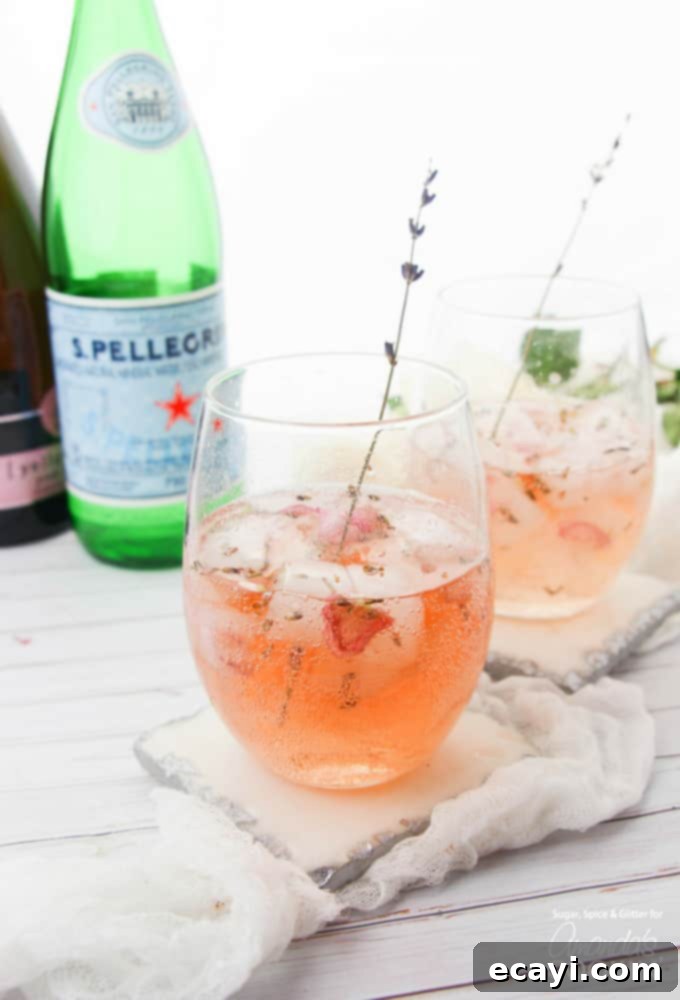 Lavender Rose Spritzer: made with fresh lavender, rose petals and rosé! Perfect for brunch or bridal showers! #rosespritzer #winespritzer #summercocktails #bridalshowerdrinks #brunchcocktails #amandascookin Lavender rose spritzer in wine glasses with lavender stem garnish