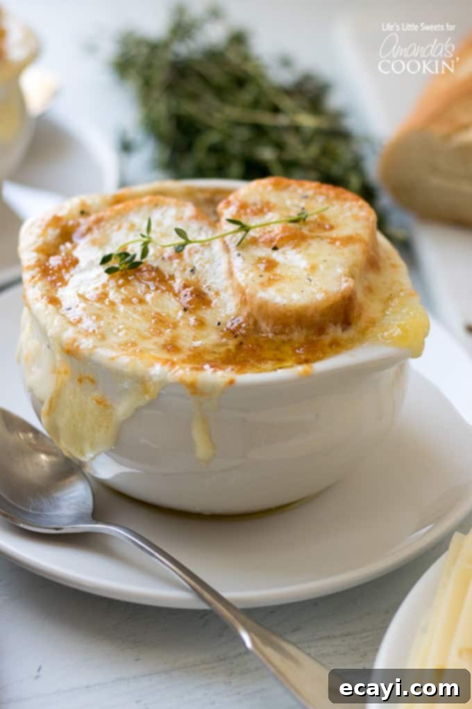 Experience the ultimate comfort with this savory French Onion Soup, featuring sweet caramelized onions, a flavorful broth, and a golden, cheesy baguette topping. Rich French Onion Soup with melted cheesy baguette topping in a ceramic bowl, ready to be enjoyed