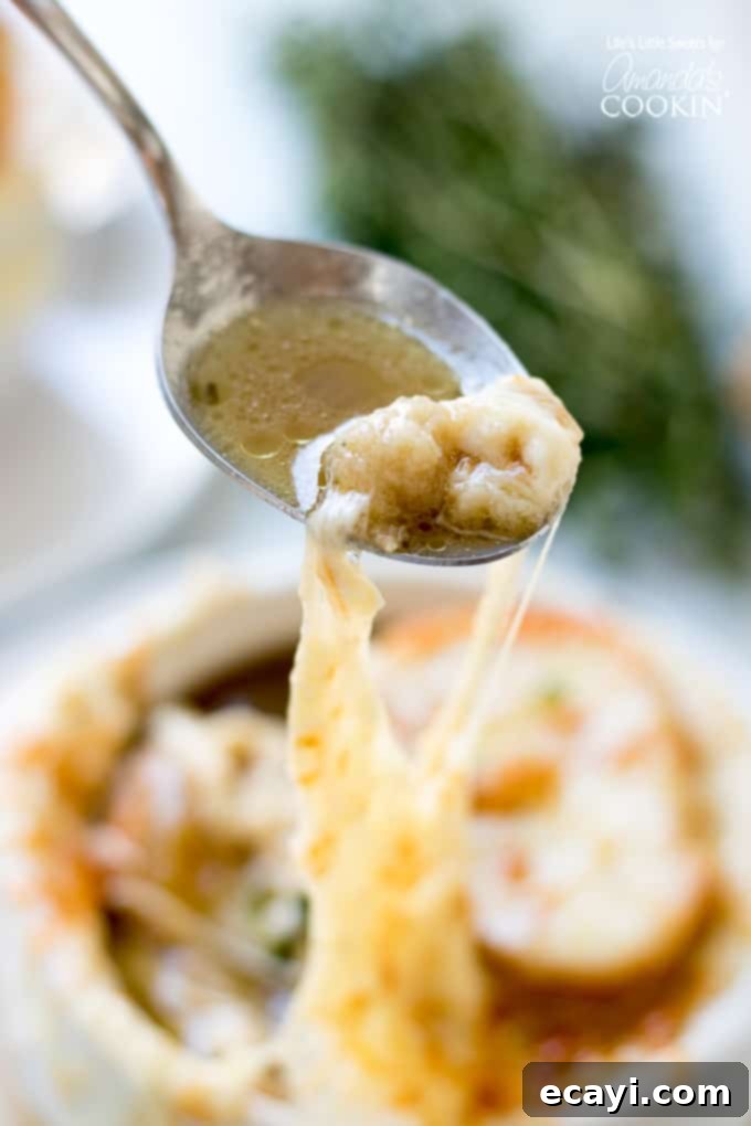 The irresistible cheese pull of a perfectly broiled French Onion Soup, promising a delightful culinary experience. French Onion Soup with a glorious string of melted cheese stretching from the bowl, demonstrating its perfect texture