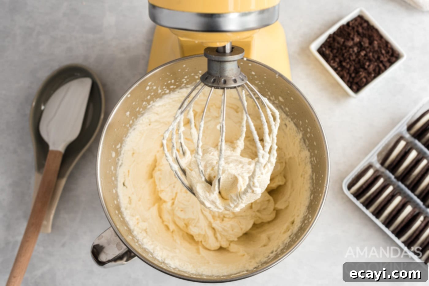 No-Bake Oreo Delight 5 Cream, powdered sugar, and vanilla being beaten together in a stand mixer bowl until stiff peaks form.