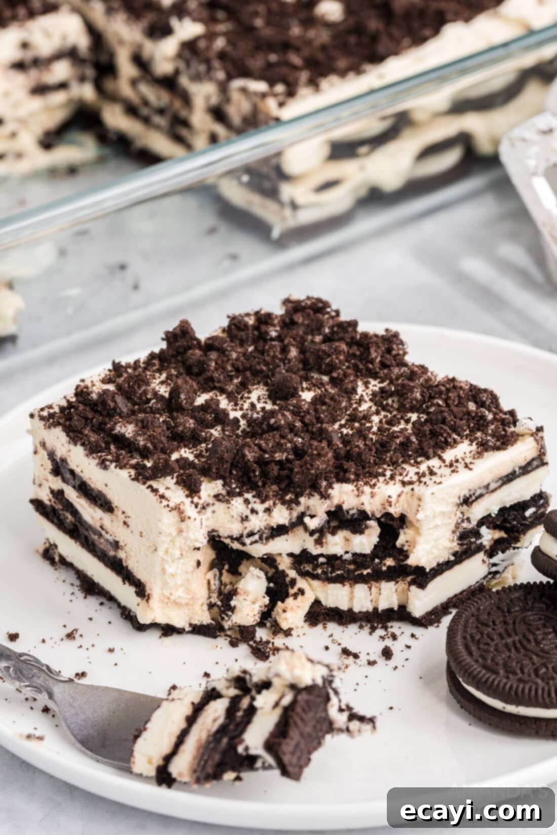 No-Bake Oreo Delight 9 A single slice of Oreo Icebox Cake on a white plate with a fork, ready to be enjoyed.