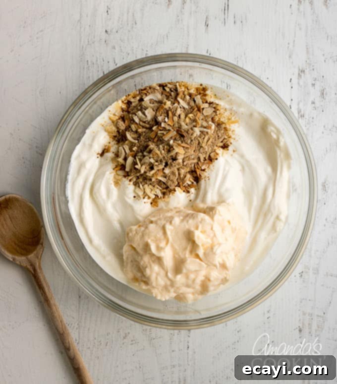Luscious Onion Swirl 4 All the creamy onion dip ingredients, including Lipton onion soup mix, Greek yogurt, and mayonnaise, are placed into a mixing bowl.