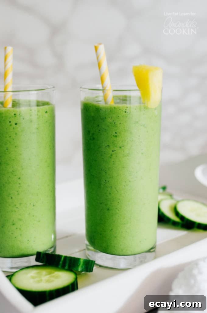 This Cucumber Tropical Smoothie packs in fruits and leafy green veggies, getting you fueled for your day (without the taste of a typical green smoothie). #tropical #smoothierecipes #tropicalsmoothie #cucumber #healthysmoothie #greensmoothie #breakfast #breakfastsmoothie Cucumber Tropical Smoothies in glass with pineapple garnish