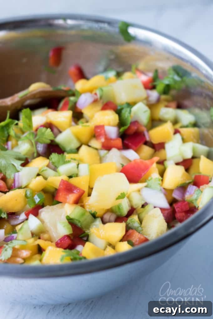 This mango salsa is full of fresh veggies and sweet fruit! Perfect for a potluck or barbecue. Fresh mangos, pineapple, cucumber, bell peppers, onion, jalapeno, and of course fresh cilantro! bowl of mango salsa