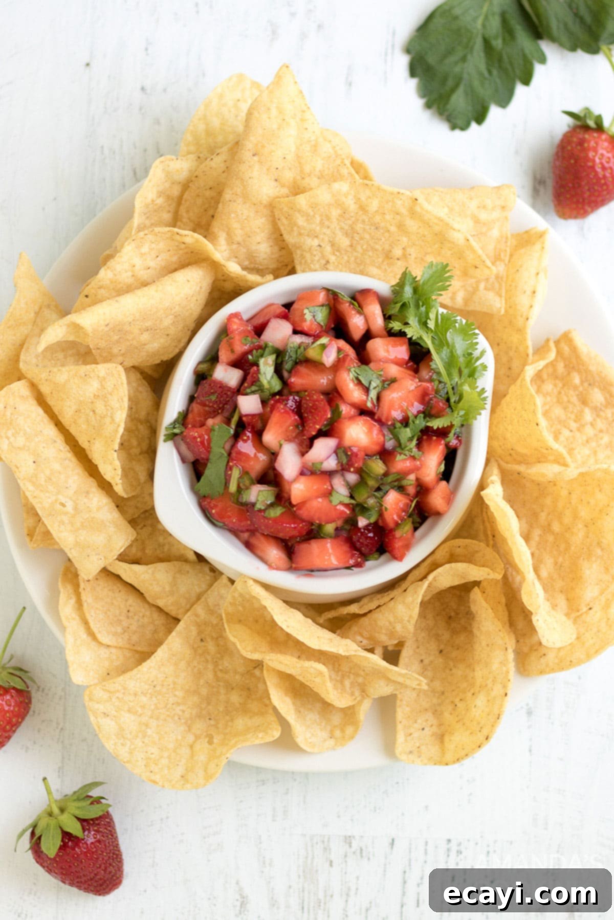 Summer Strawberry Salsa 3 An inviting overhead shot of fresh strawberry salsa nestled in a bowl, surrounded by golden, crispy tortilla chips, ready for dipping.