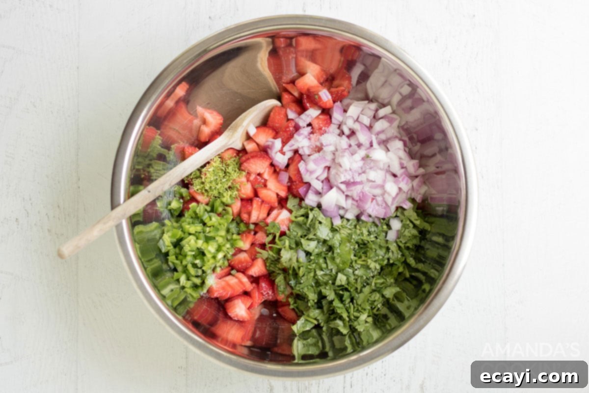 Summer Strawberry Salsa 5 Freshly diced strawberries, minced jalapeño, chopped red onion, cilantro, and lime zest are combined in a sleek silver mixing bowl, ready to be transformed into vibrant salsa.