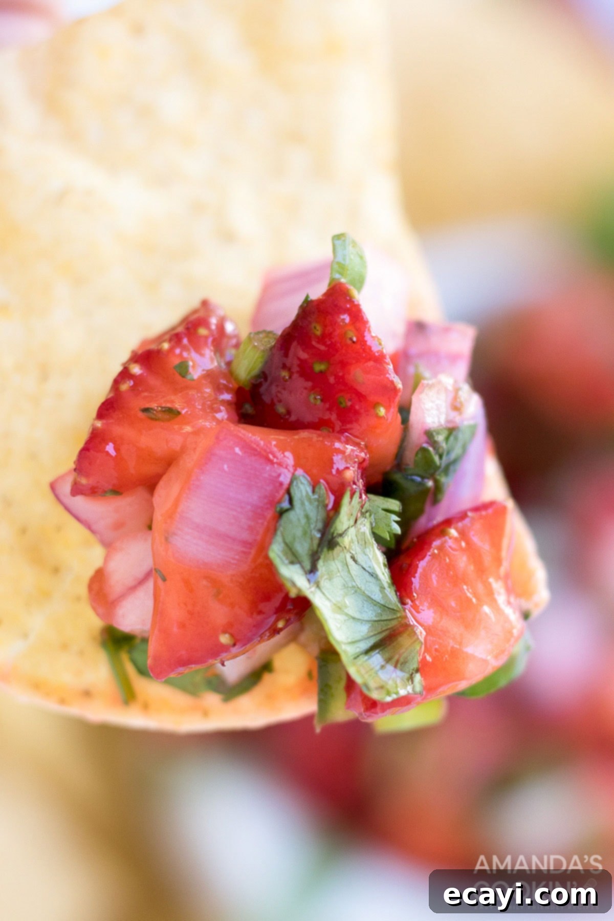Summer Strawberry Salsa 7 A close-up shot of a single tortilla chip perfectly loaded with vibrant strawberry salsa, highlighting its delicious texture and fresh ingredients.