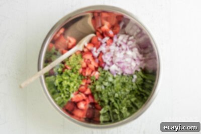 Summer Strawberry Salsa 9 Freshly diced strawberries, minced jalapeño, chopped red onion, cilantro, and lime zest are combined in a sleek silver mixing bowl, ready to be transformed into vibrant salsa.
