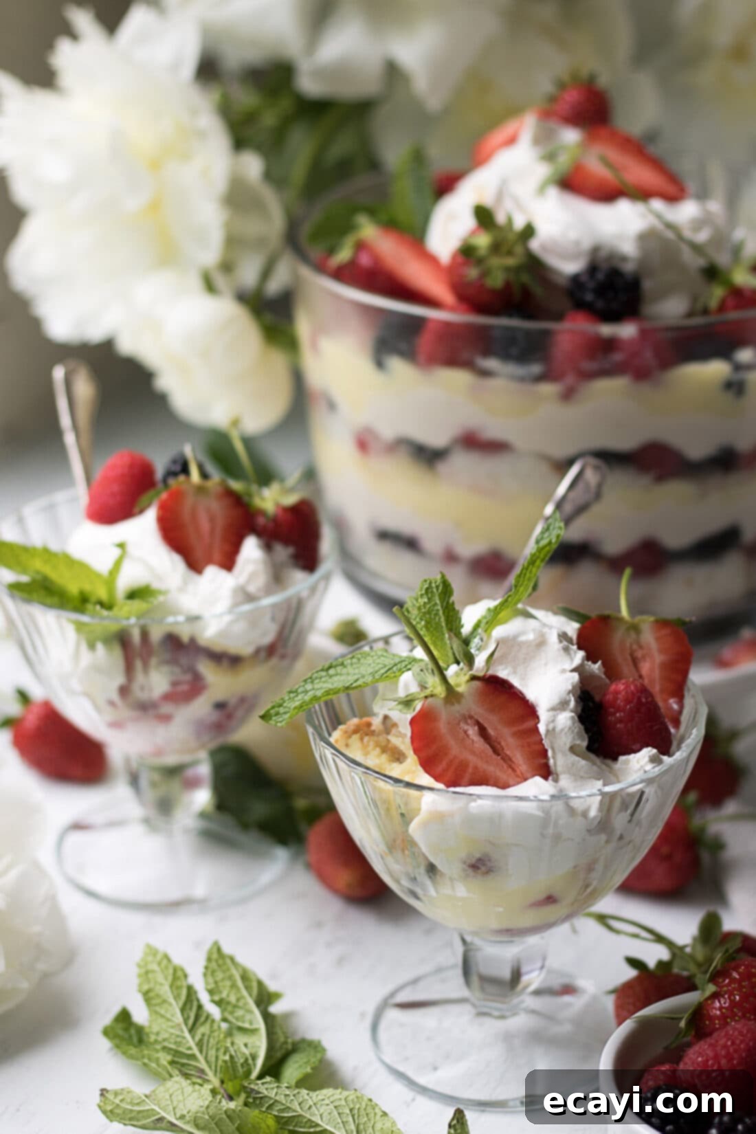 Mixed Berry Trifle served in individual portions. Individual servings of Mixed Berry Trifle presented in clear sundae cups, showing the layered components.