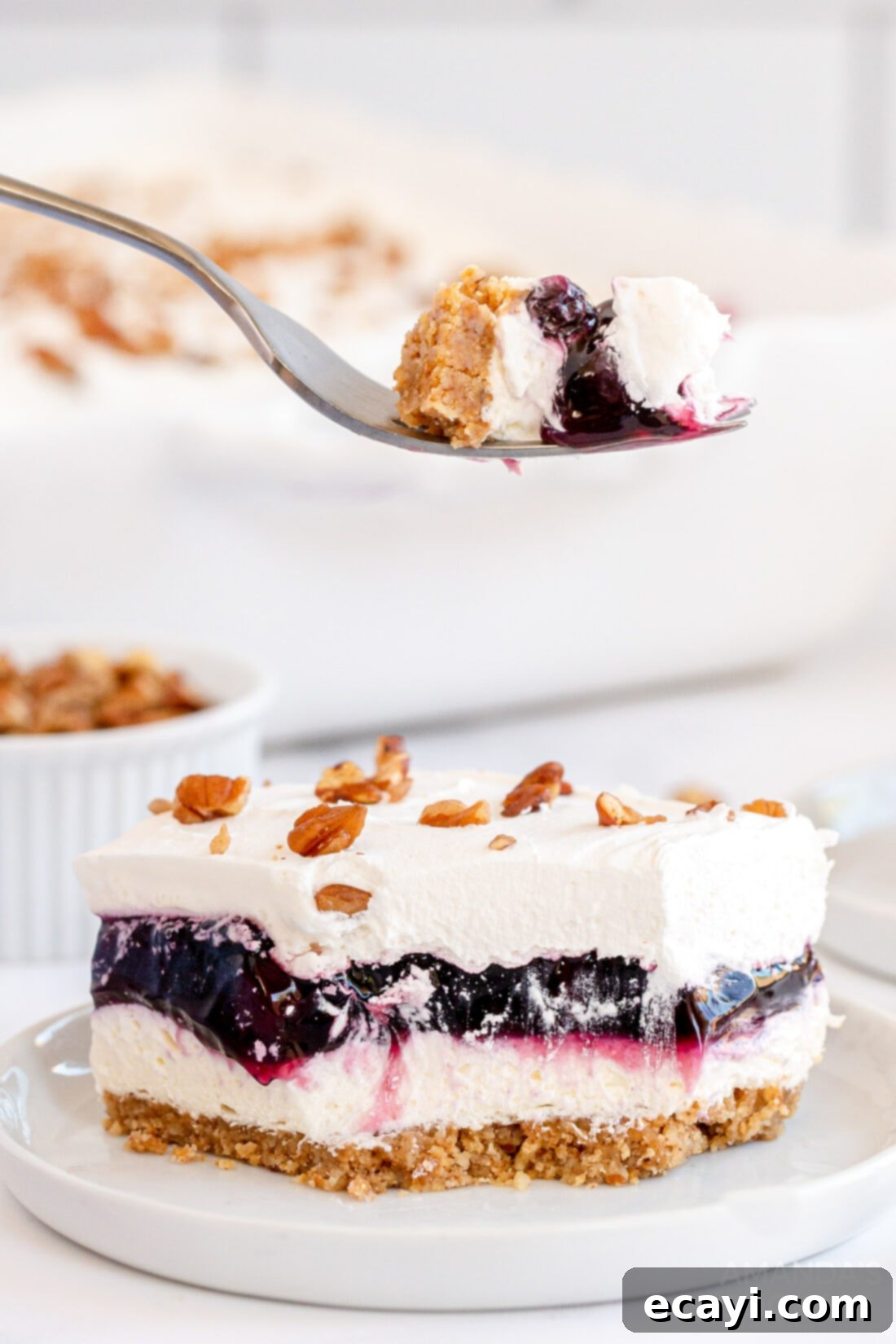 Blueberry Bliss 2 A delectable forkful of Blueberry Delight held above a generous slice of the layered dessert, showcasing its beautiful textures.
