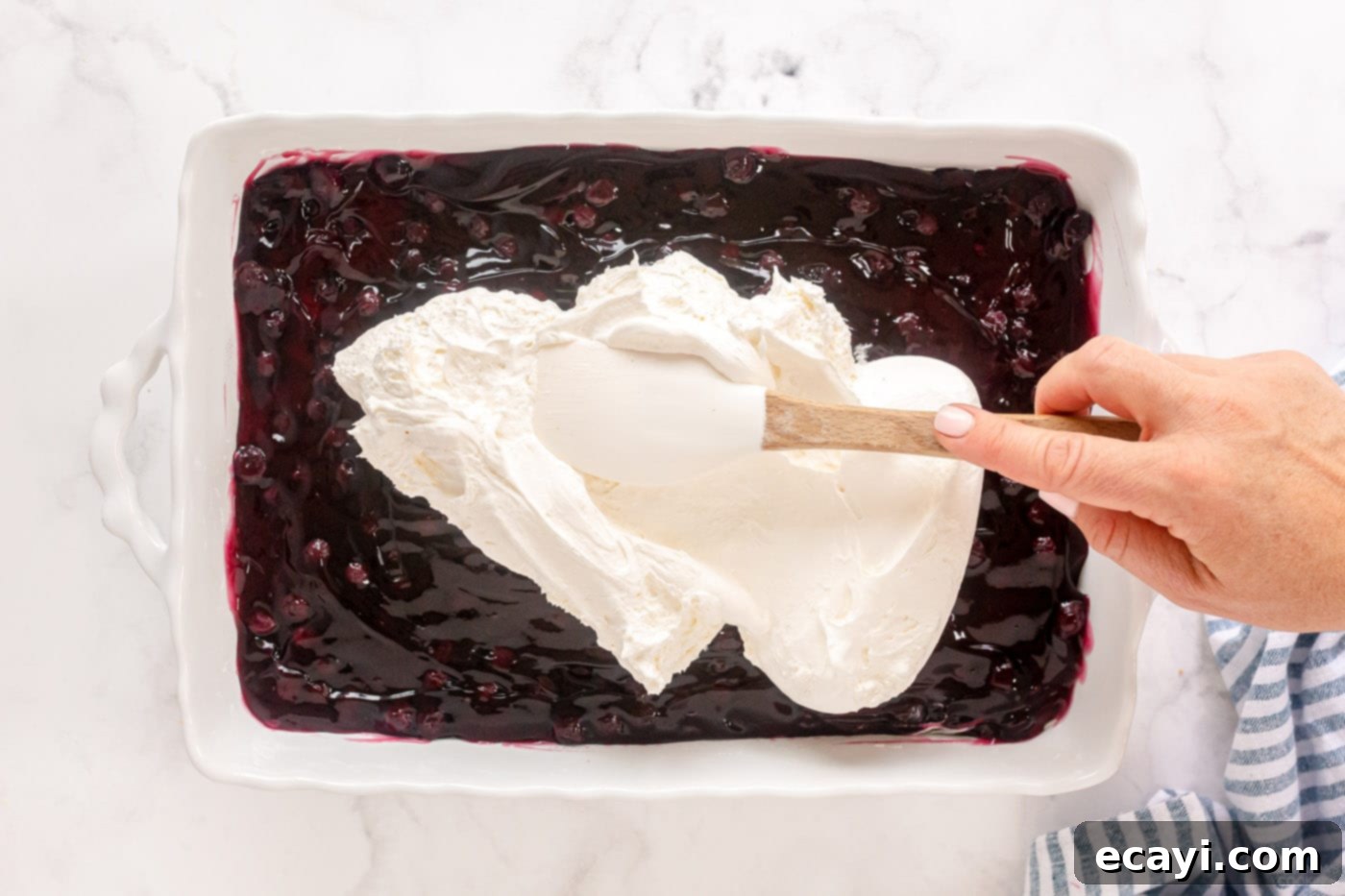 Blueberry Bliss 12 Spreading the final layer of whipped topping smoothly over the blueberry pie filling, completing the layered dessert.