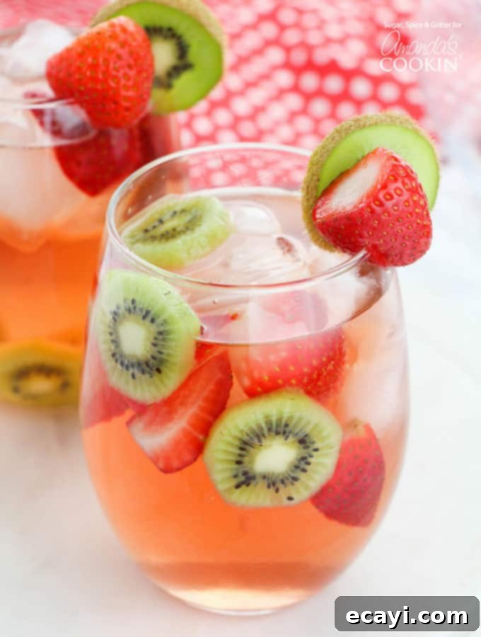 Sparkling Raspberry Gin Rickey 2 Refreshing strawberry kiwi sangria in a pitcher with glasses, garnished with fresh fruit.