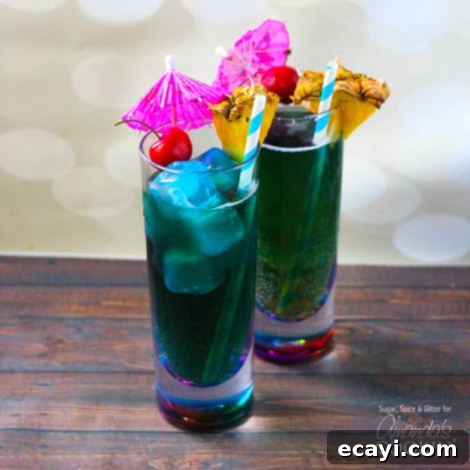 Sparkling Raspberry Gin Rickey 3 Two vibrant blue mermaid cocktails in elegant hurricane glasses, garnished with citrus slices and cherries.