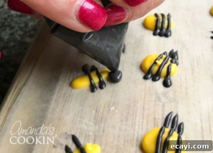 Sweet Honeybee Crowns 5 Piping the black candy melt head onto a yellow oval bee body, demonstrating precision