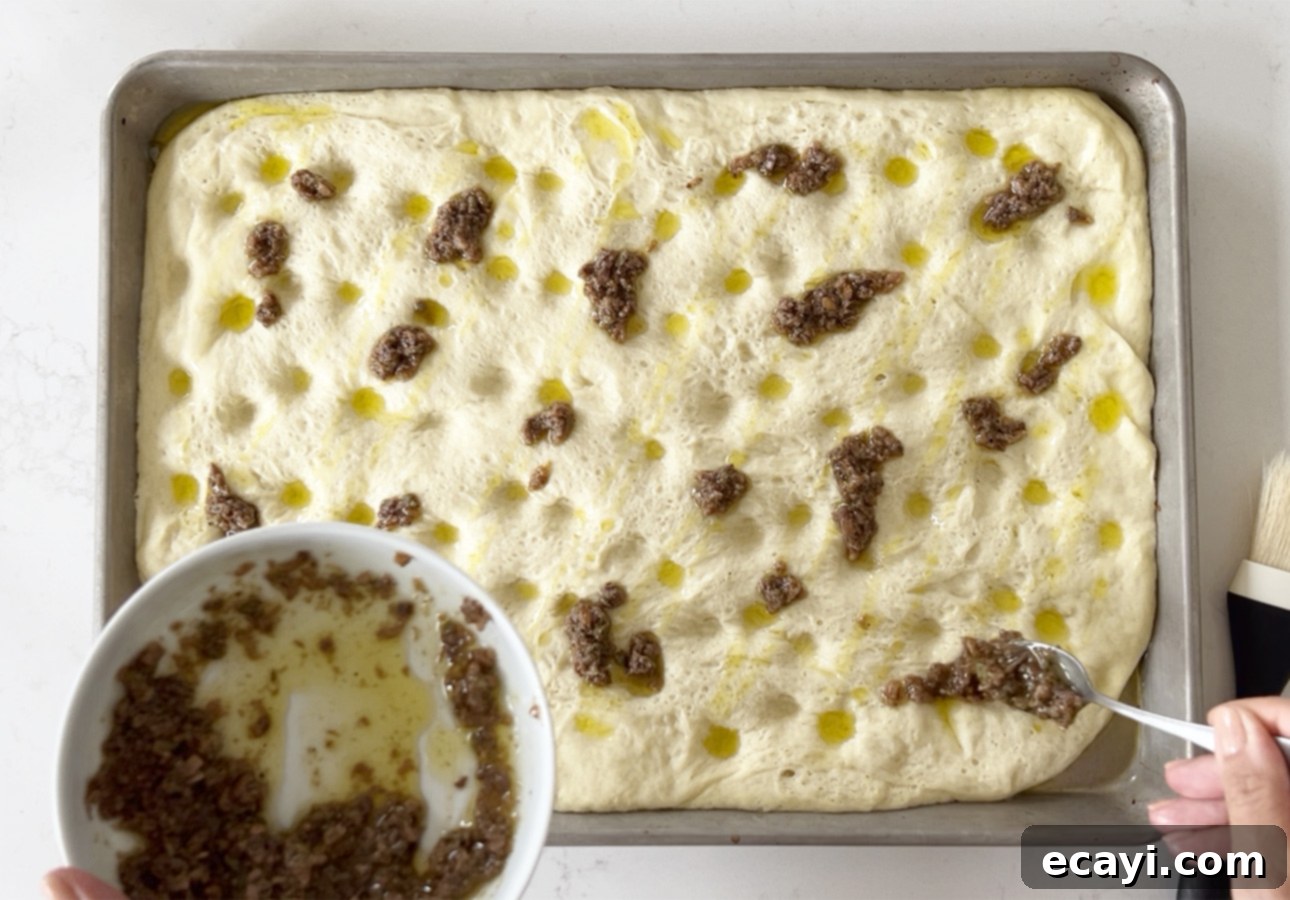 Golden Perfection Pissaladière A Provençal Onion and Anchovy Flatbread 22 Spreading anchovy dressing over pissaladière dough // FoodNouveau.com