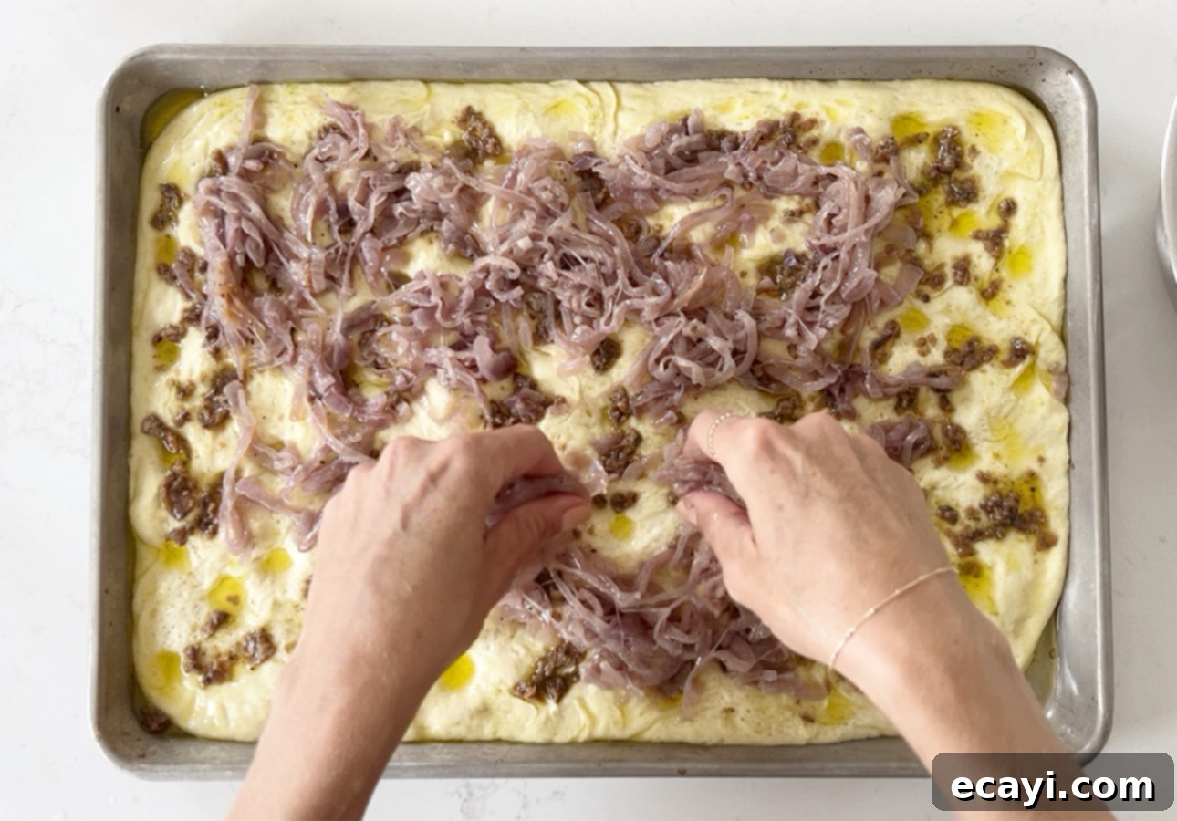 Golden Perfection Pissaladière A Provençal Onion and Anchovy Flatbread 24 Adding caramelized onions over flatbread dough // FoodNouveau.com