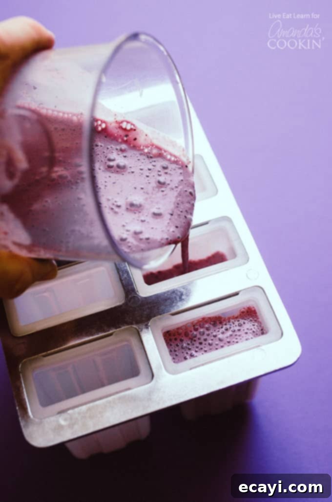 Easy preparation: pouring blueberry cheesecake mixture into molds Pouring the creamy blueberry cheesecake mixture into a popsicle mold