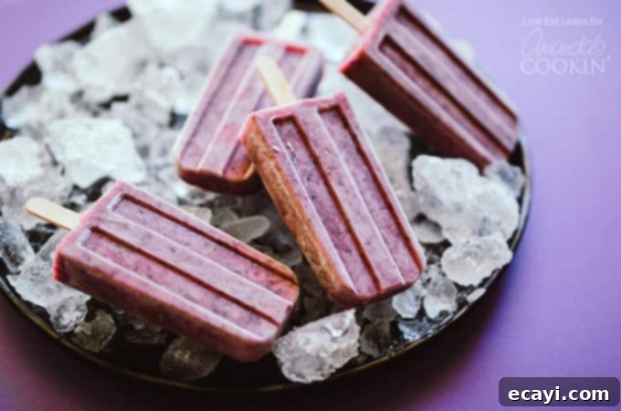 Refreshing blueberry cheesecake popsicles for summer Several blueberry cheesecake popsicles lying on a bed of ice, ready to be picked up