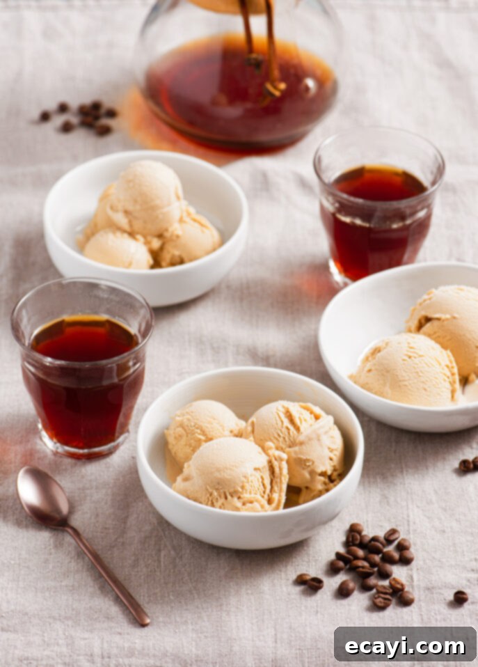 Rich Coffee Gelato 9 Three white bowls with scoops of coffee gelato, two glasses and a carafe of black coffee, some coffee beans, and a spoon, all arranged on a light linen tablecloth. // FoodNouveau.com