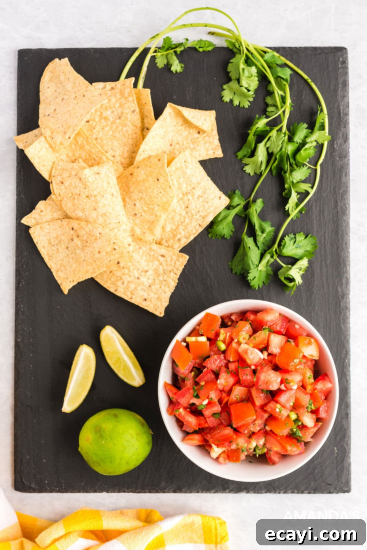 Delicious homemade salsa fresca, perfectly presented for dipping A vibrant bowl of homemade salsa fresca, surrounded by tortilla chips, fresh cilantro, and lime wedges on a rustic black board