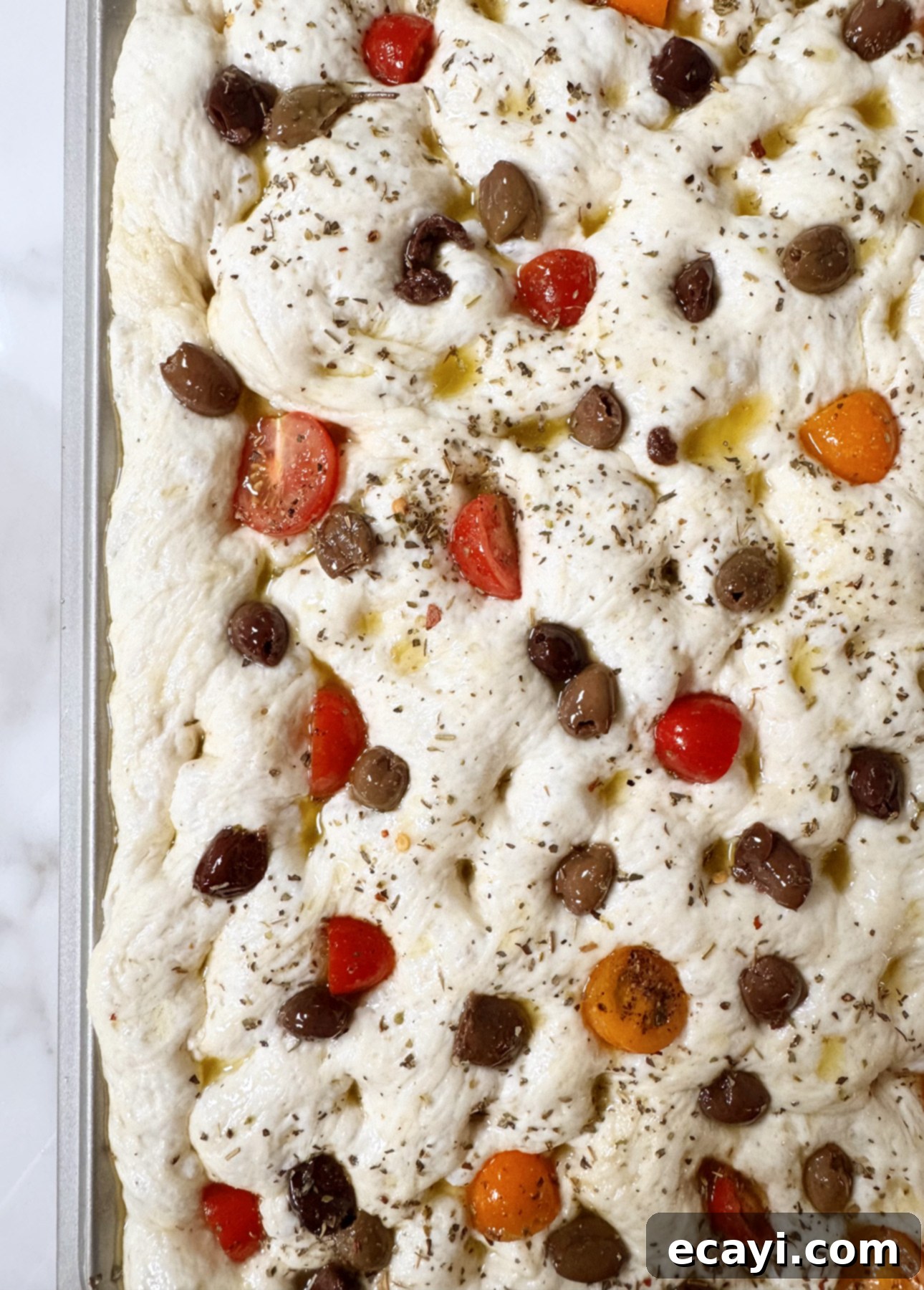Bake Perfect No-Knead Focaccia Effortlessly 17 No-Knead Focaccia topped with olives, cherry tomatoes, and oregano, traditional garnishes for the Italian bread // FoodNouveau.com