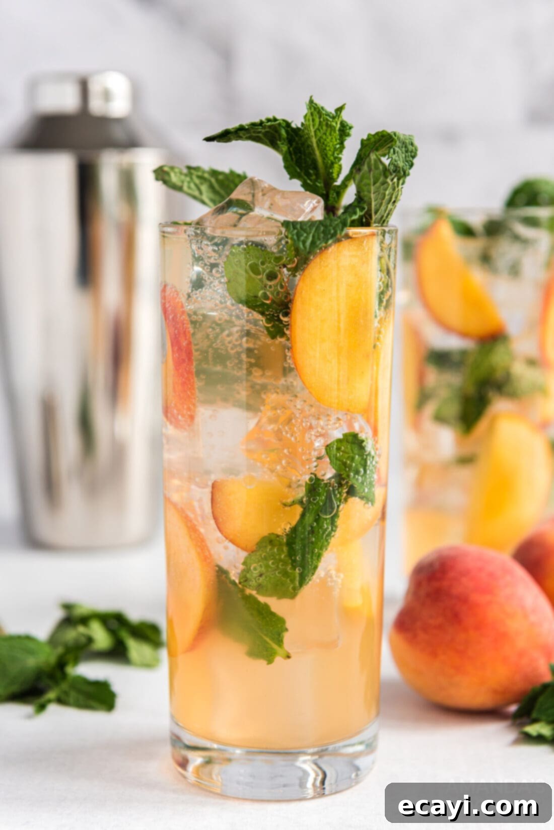 Peach Paradise Mojito 2 Two tall glasses of homemade Peach Mojito, garnished with fresh peach slices and mint leaves, ready for summer enjoyment.