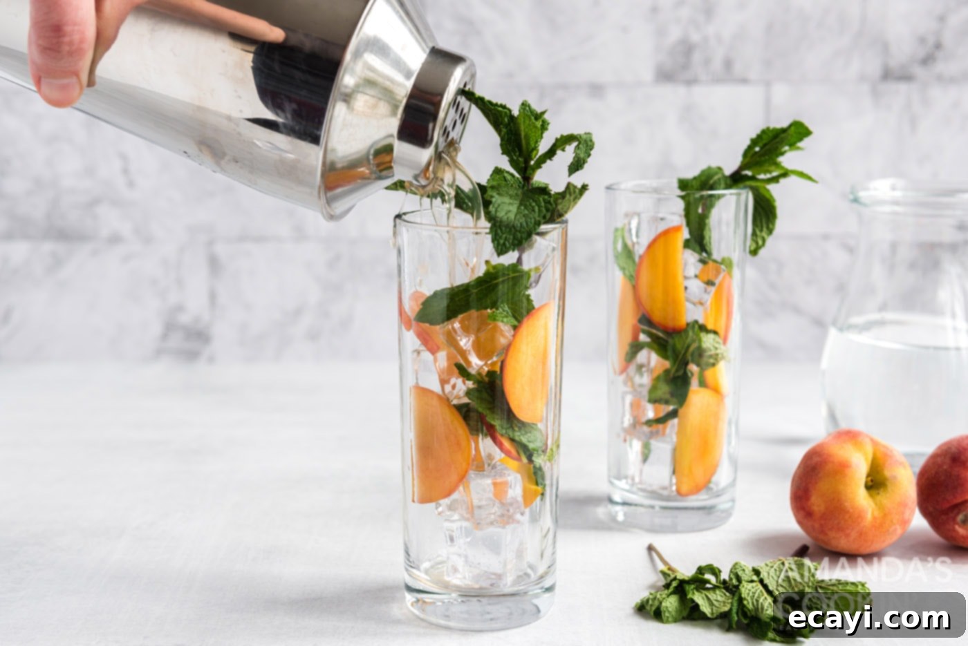 Peach Paradise Mojito 8 cocktail shaker pouring peach mojito into glass with peaches and mint