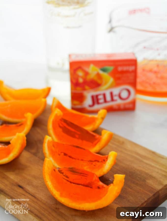 These orange Jell-O shots are the perfect party treat with a creamsicle twist! Bright orange Jell-O set within half orange rinds, arranged on a tray, ready to be sliced for a party.