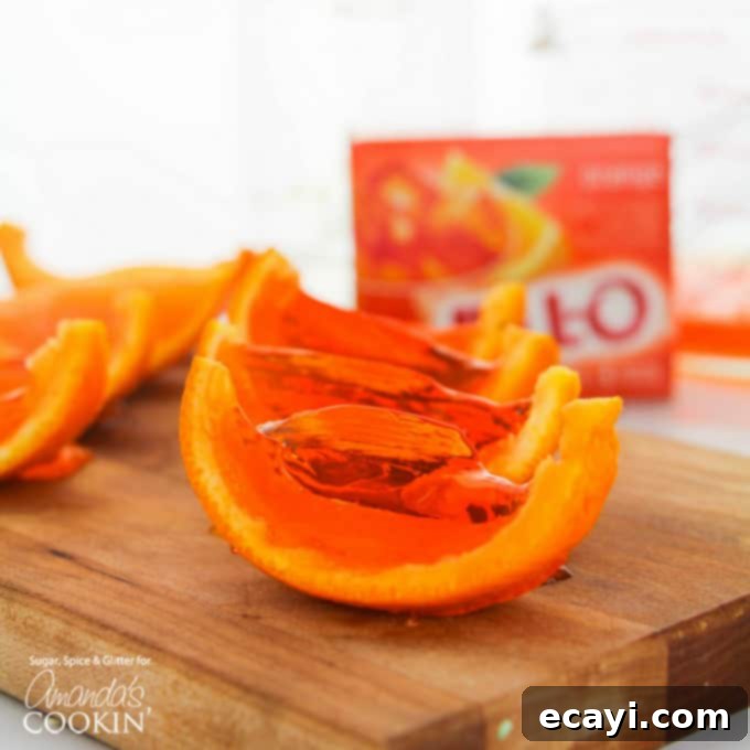 Orange Jell-O Shots: A vibrant and zesty party favorite. Close-up of bright orange Jell-O shots presented in sliced orange rinds, showcasing their vibrant color and neat cuts.