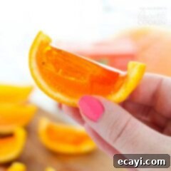 Sunny Orange Boozy Bites 2 Vibrant orange jello shots meticulously crafted and set within the hollowed orange rinds, arranged for presentation.