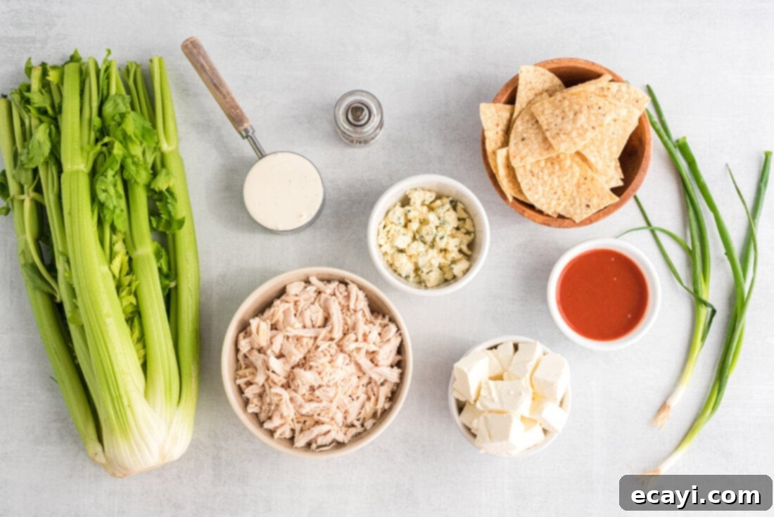 Ultimate Buffalo Chicken Dip 4 A flat lay photograph displaying all the ingredients needed for Buffalo Chicken Dip: shredded chicken, cream cheese, blue cheese, hot sauce, ranch dressing, and black pepper.