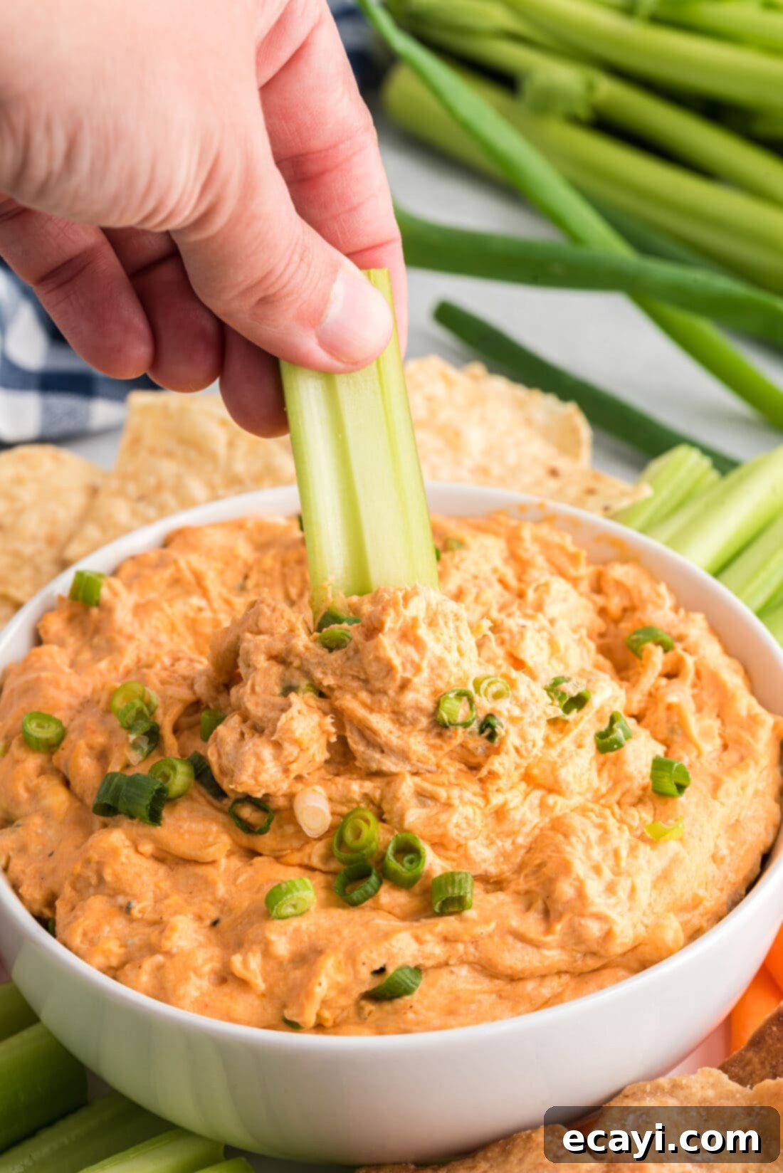 Ultimate Buffalo Chicken Dip 9 A crisp celery stick being dipped into a bowl of Buffalo Chicken Dip, ready to be enjoyed as a classic pairing.