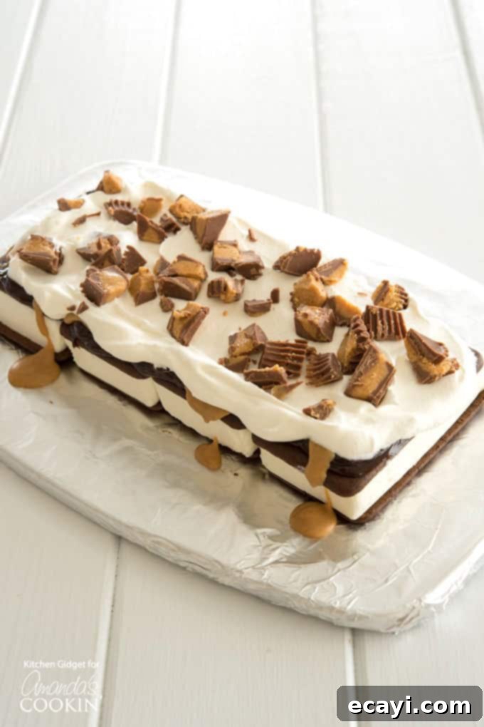 Adding Chopped Peanut Butter Cups to Cake A close-up of chopped mini Reese's peanut butter cups being sprinkled onto the ice cream sandwich layers.
